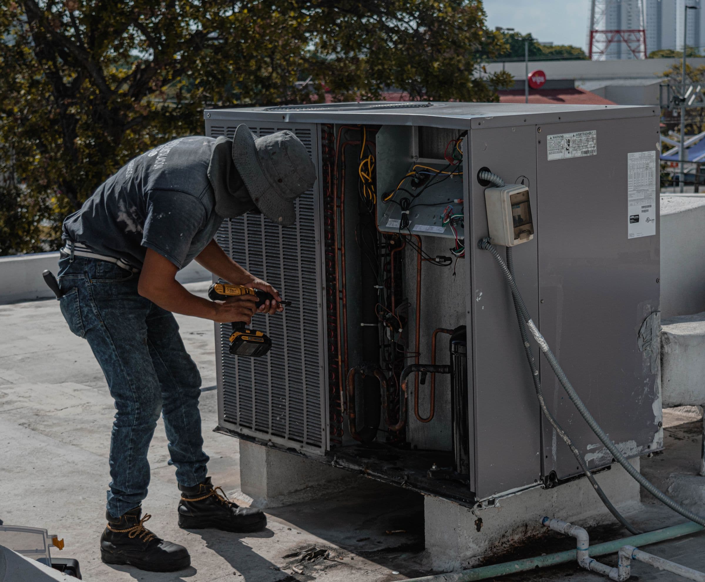 Técnico reparando un condensador de refrigeración comercial en una terraza